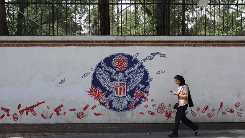 A woman walks past an anti-US mural on a street in Tehran