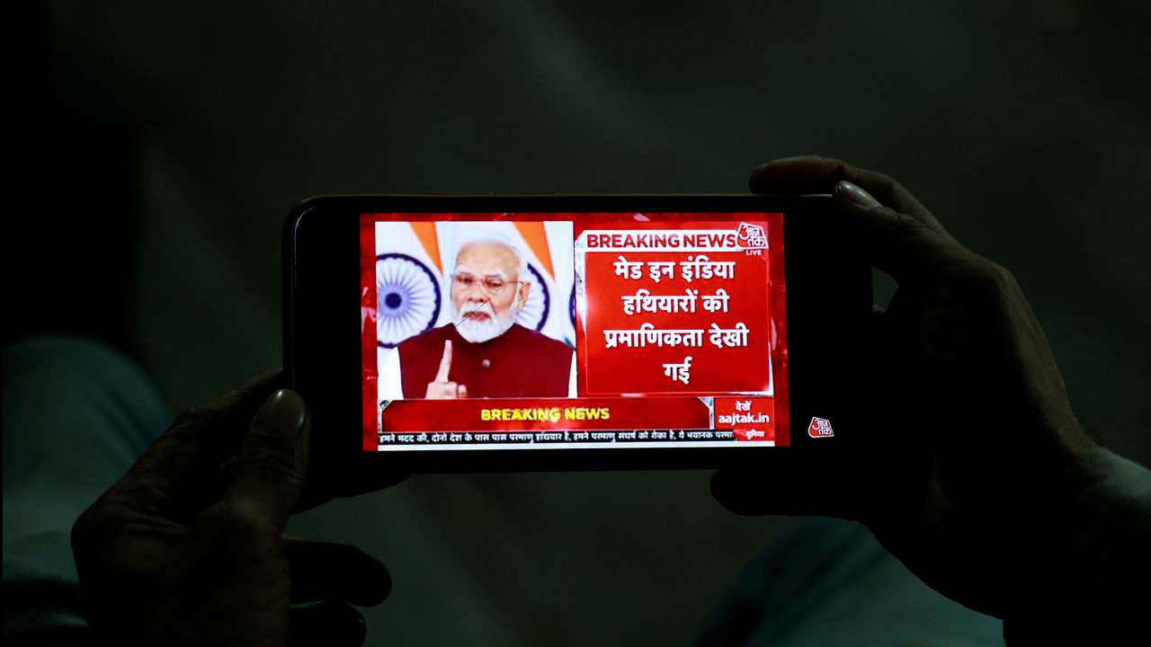 A man watches as PM Modi delivers an address to the nation, on a mobile phone in the old quarters of Delhi