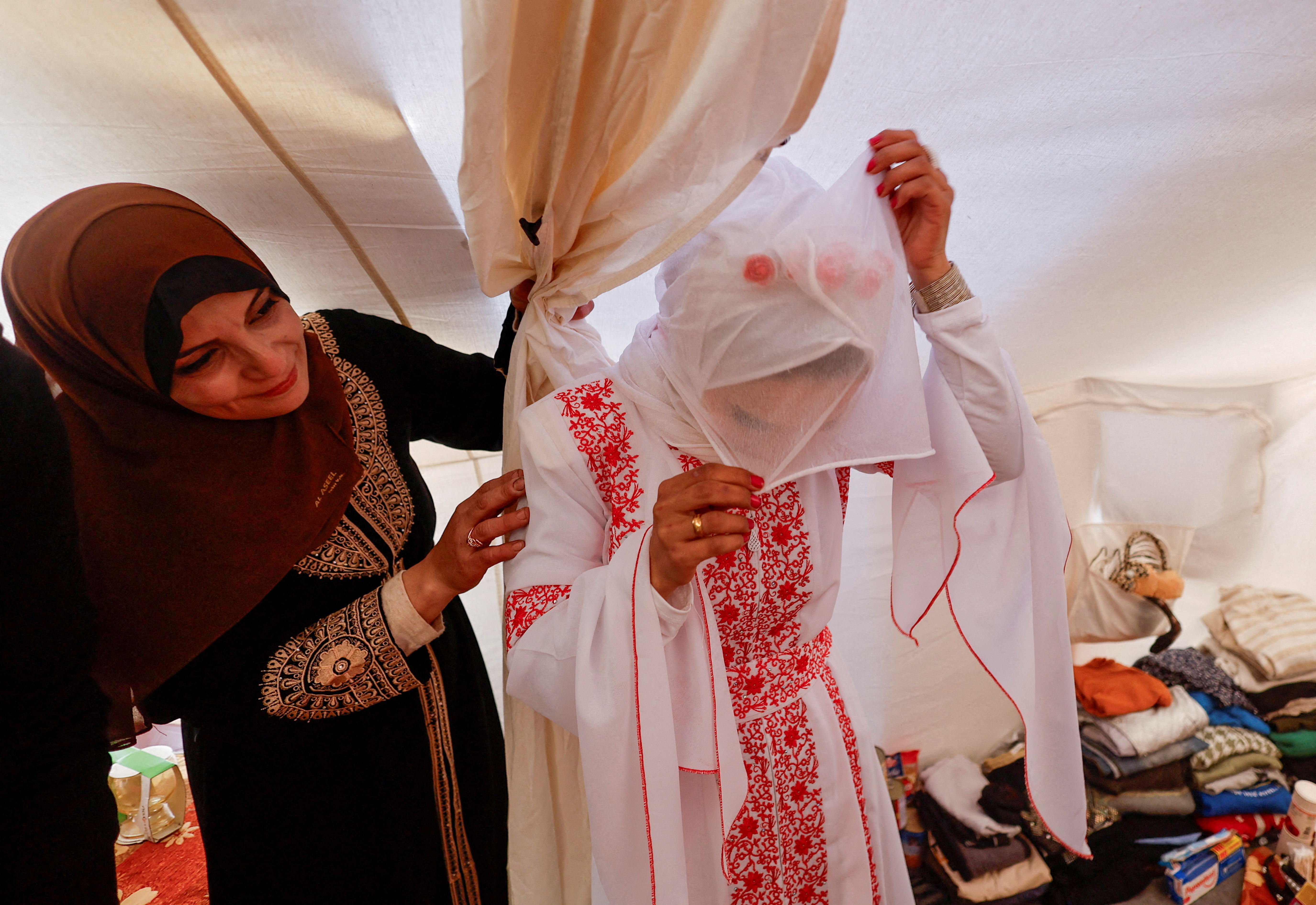 A Palestinian bride adjusts her veil in a tent camp on her wedding day in Rafah