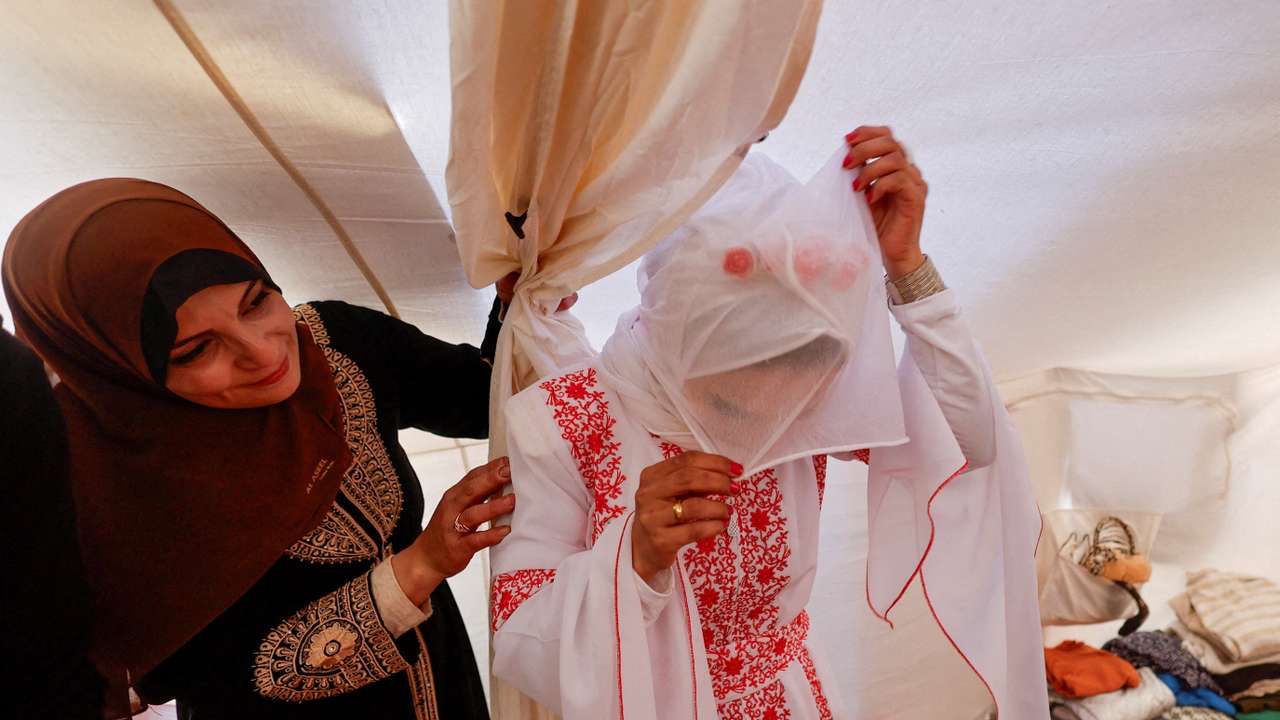 A Palestinian bride adjusts her veil in a tent camp on her wedding day in Rafah