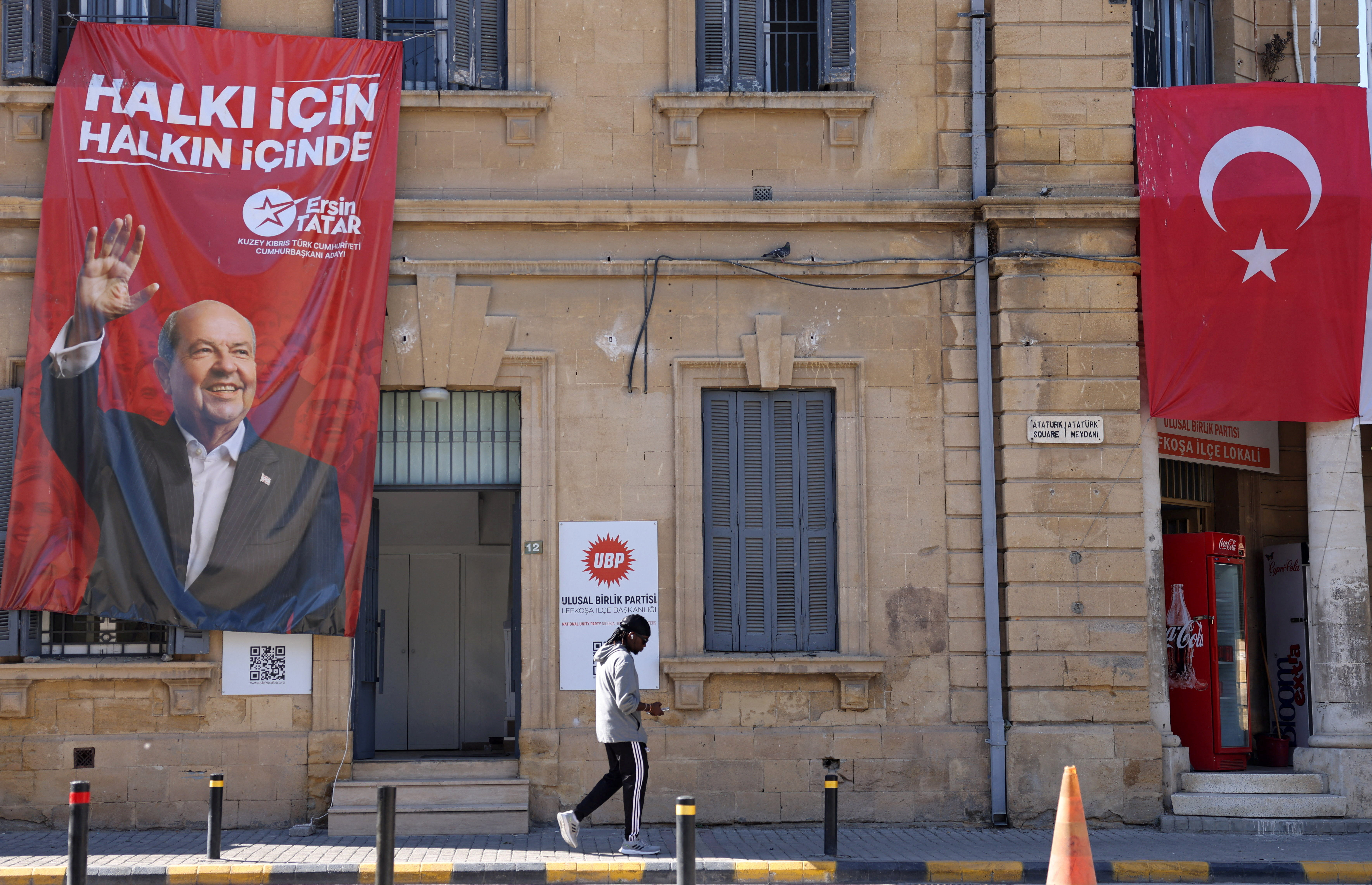 A person walks past a campaign poster of Turkish Cypriot leader and candidate Ersin Tatar ahead of the Turkish Cypriot presidential election