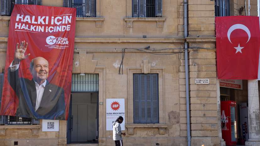A person walks past a campaign poster of Turkish Cypriot leader and candidate Ersin Tatar ahead of the Turkish Cypriot presidential election