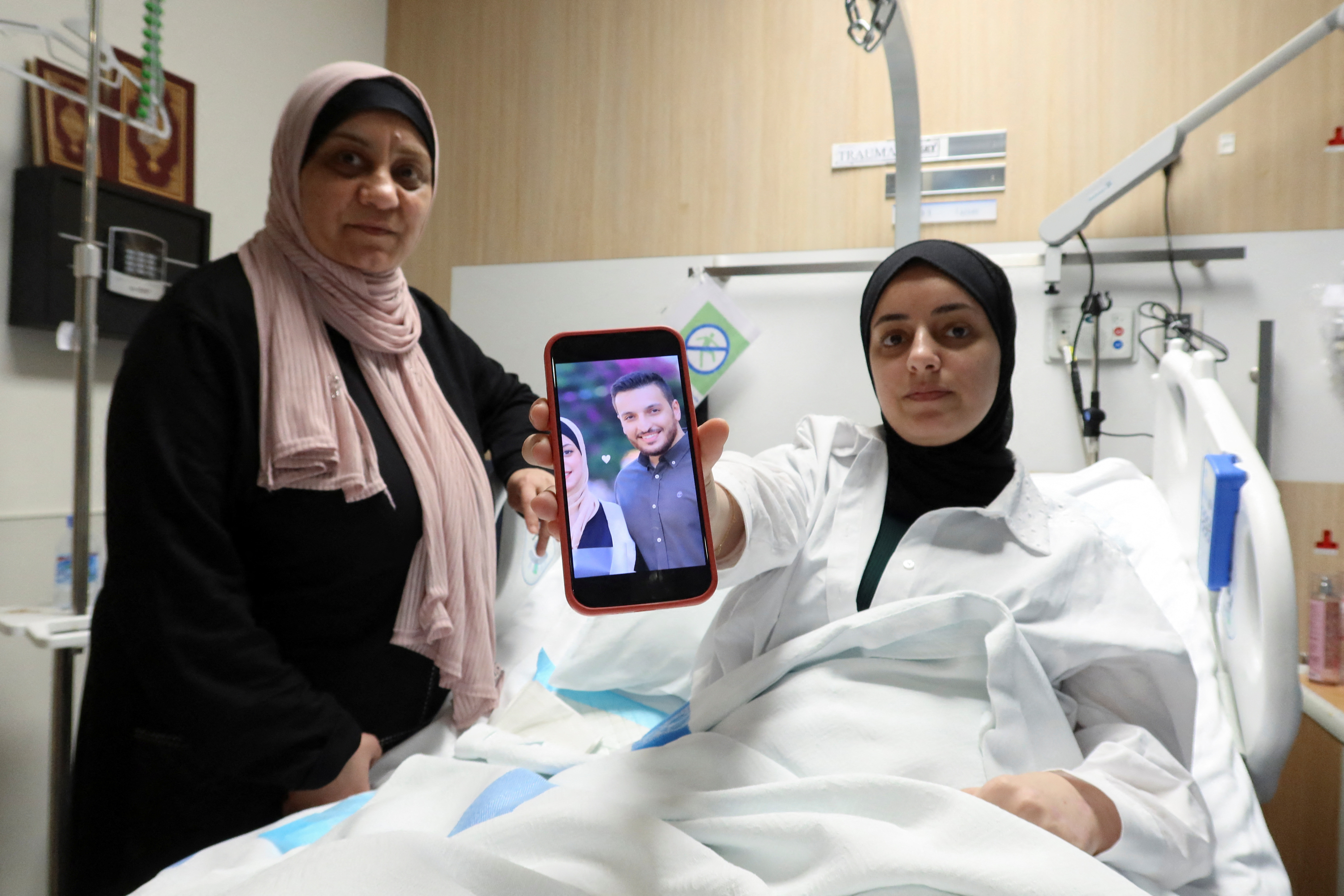 Shahed Al-Kotati, a wounded from Gaza, shows the picture of her killed husband as she sits in bed at a hospital in Doha