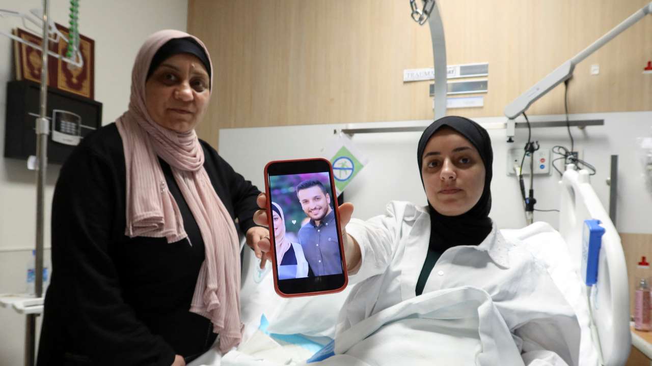 Shahed Al-Kotati, a wounded from Gaza, shows the picture of her killed husband as she sits in bed at a hospital in Doha
