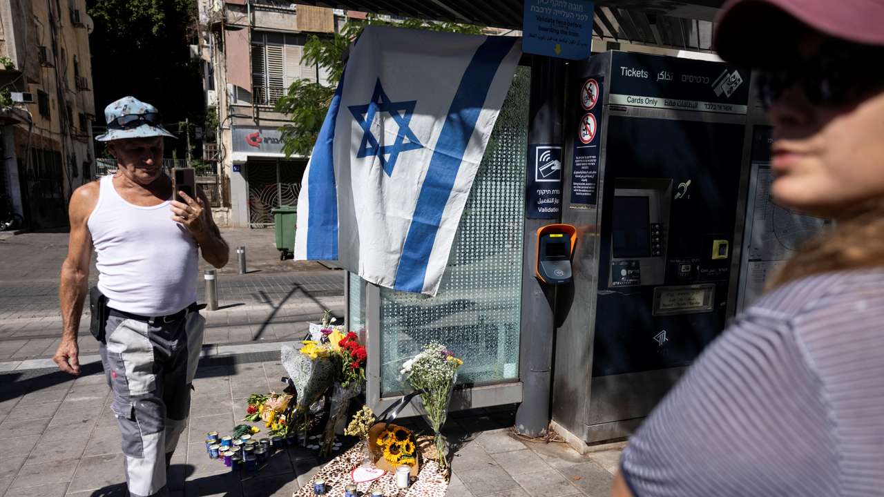 A man walks by flowers laid as a sign of respect for the people killed the evening before in a fatal shooting attack in Jaffa