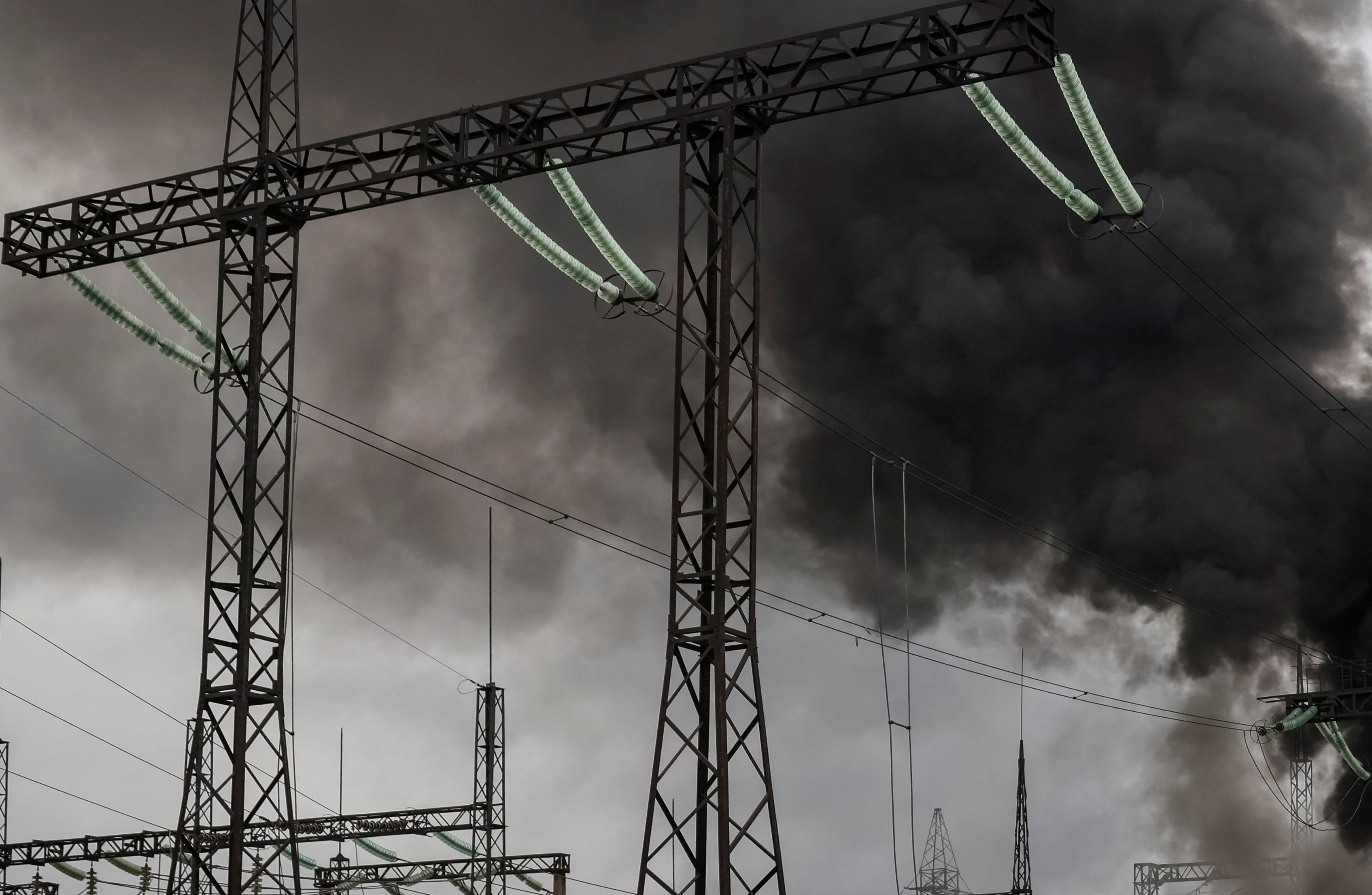 Smoke rises in the sky over a high-voltage line at a site of a Russian missile strike outside Kharkiv