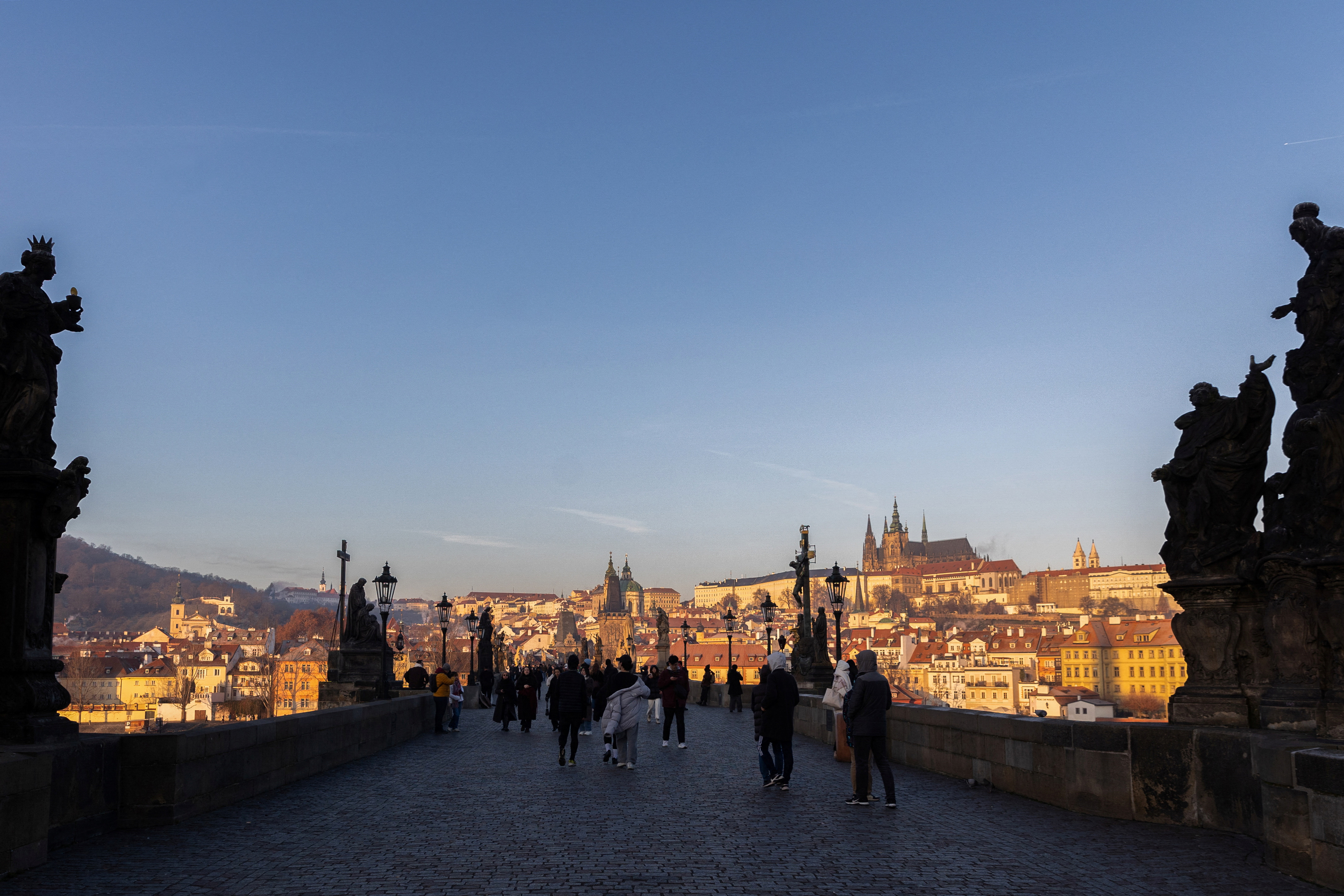 People walk across the medieval Charles Bridge in Prague