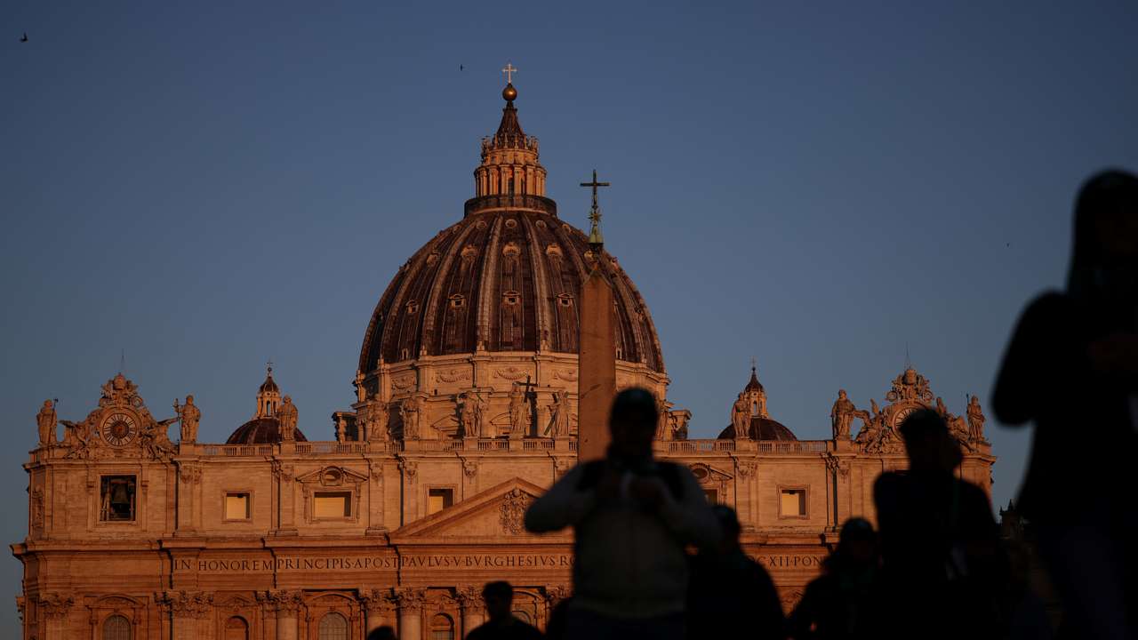 People walk in front of St. Peter's Basilica in St. Peter's Square ahead of the conclave, which will be held on May 7, at the Vatican