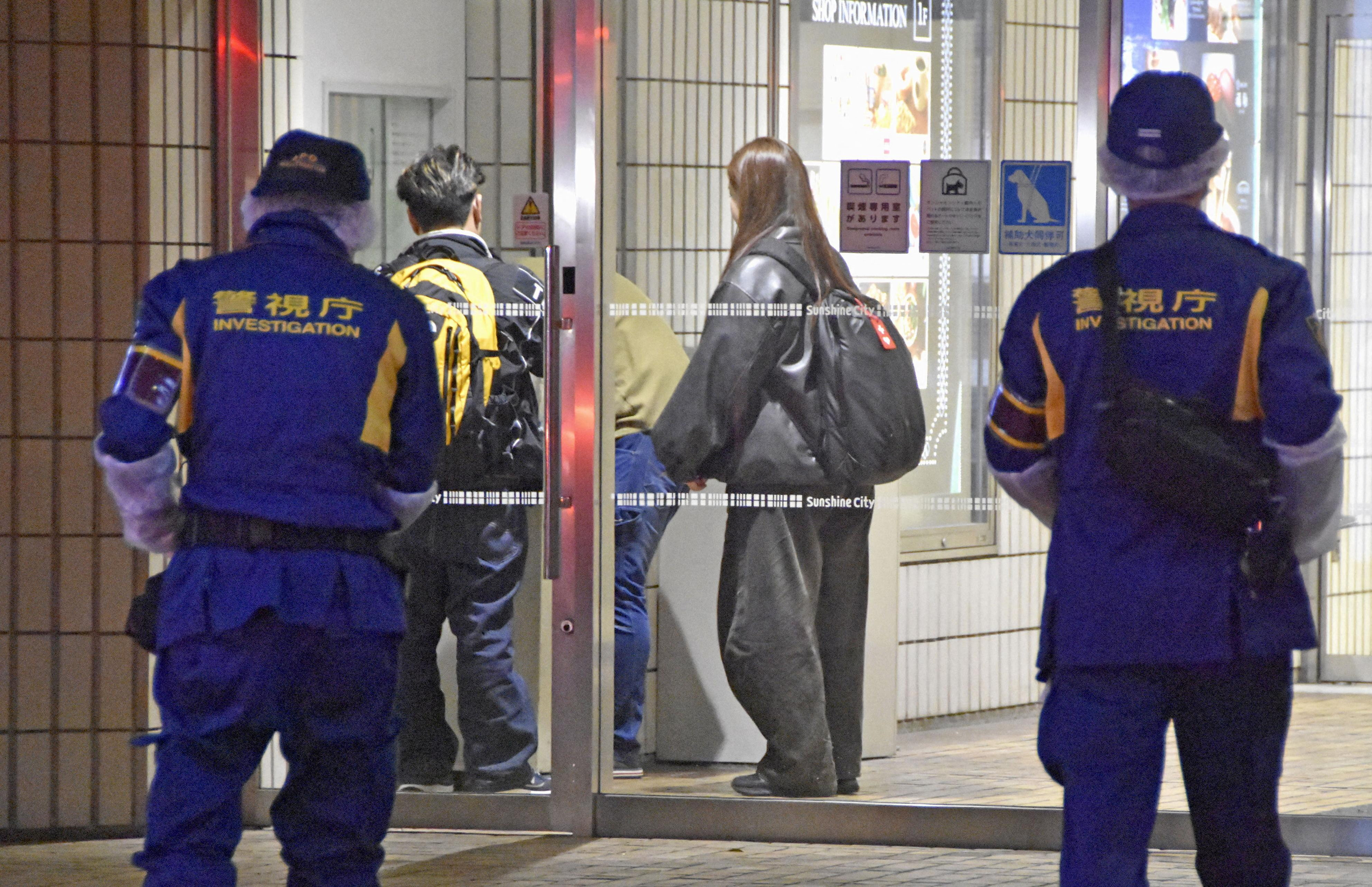 Police officers walk toward a commercial complex where a female employee at a Pokemon merchandise shop was stabbed to death at Ikebukuro district in Tokyo