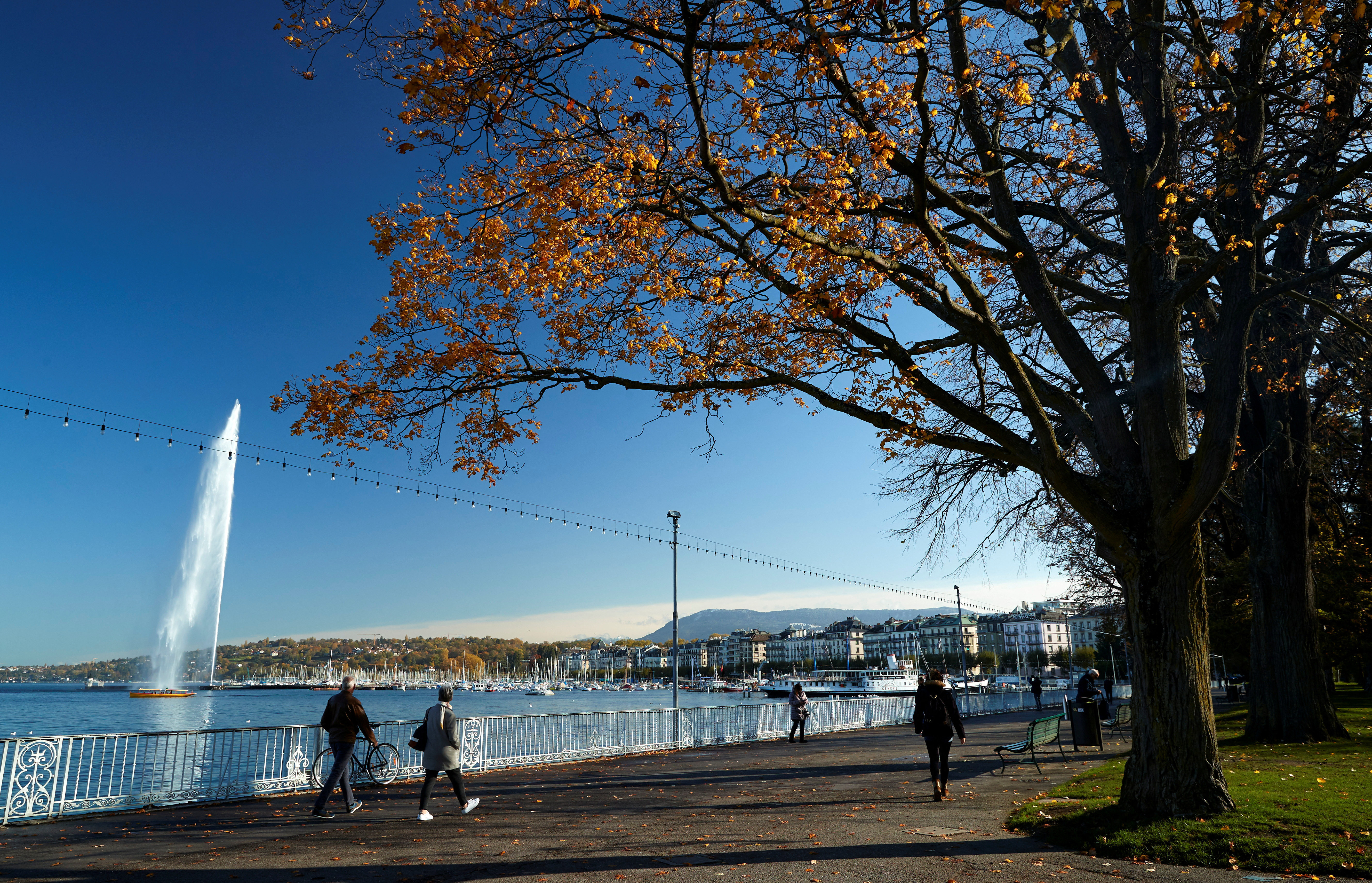 FILE PHOTO: People walk near lake Leamn and the jet d'eau water fountain in Geneva