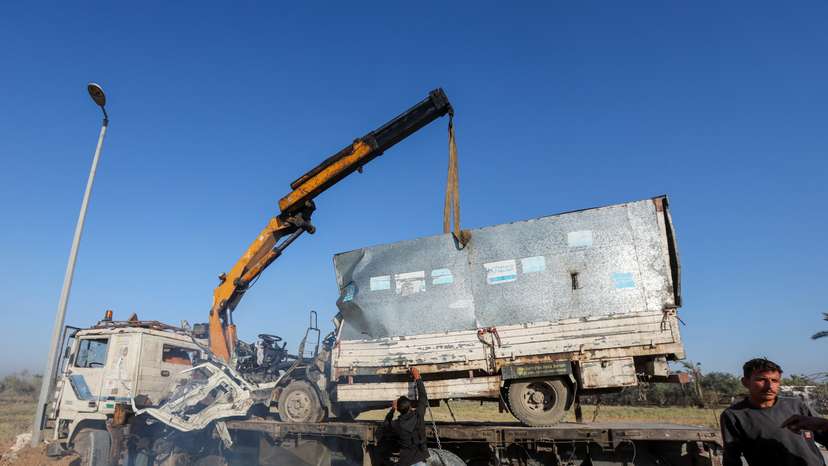 Palestinians work to remove an UNRWA-labelled vehicle after it was hit in an Israeli strike, according to Palestinian officials, amid the Israel-Hamas conflict, in Deir Al-Balah in the central Gaza Strip