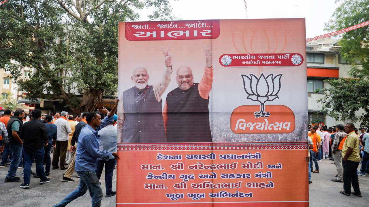 Supporters of India's ruling Bharatiya Janata Party (BJP) carry a hoarding of Indian Prime Minister Narendra Modi and Union Minister of Home Affairs Amit Shah for celebrations in Ahmedabad