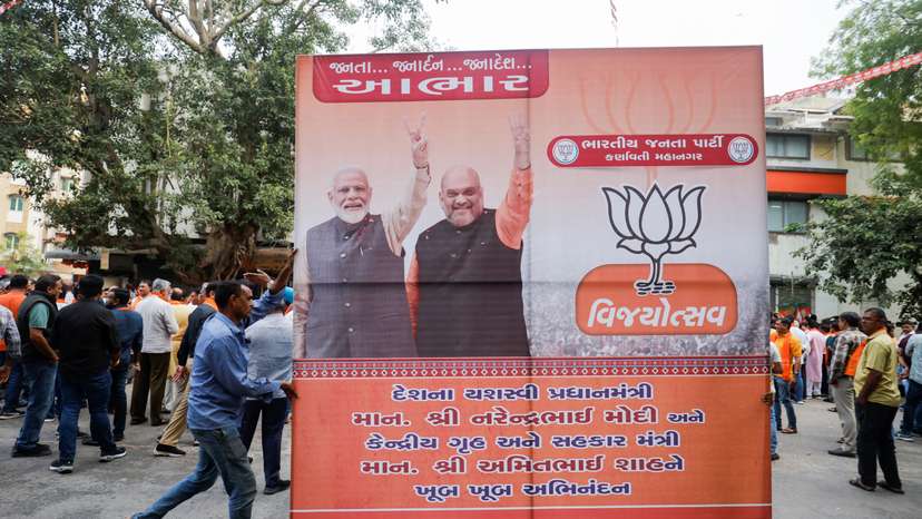 Supporters of India's ruling Bharatiya Janata Party (BJP) carry a hoarding of Indian Prime Minister Narendra Modi and Union Minister of Home Affairs Amit Shah for celebrations in Ahmedabad