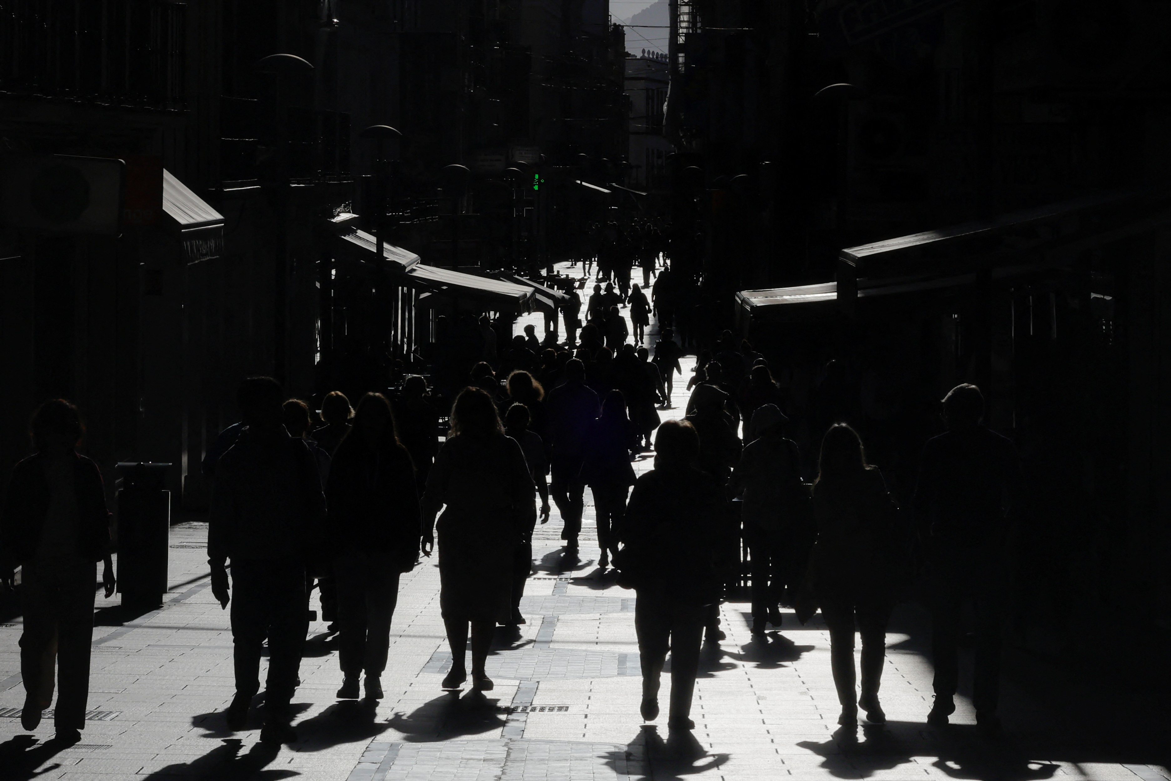 People walk along La Bola shopping street during sunset in Ronda