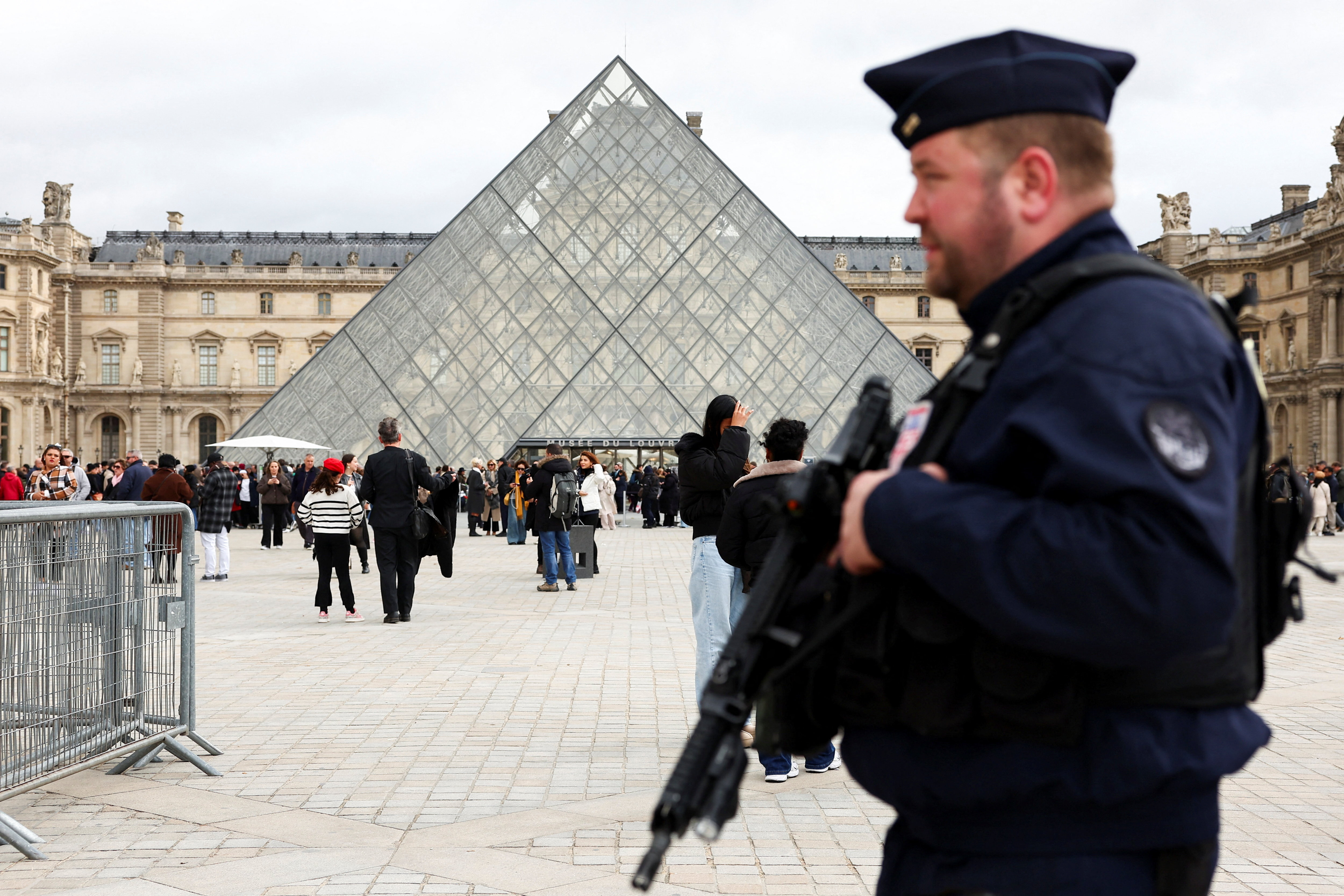 A French CRS riot police officer patrols near the glass Pyramid of the Louvre Museum