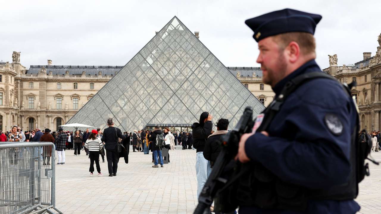 A French CRS riot police officer patrols near the glass Pyramid of the Louvre Museum