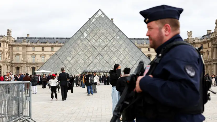 A French CRS riot police officer patrols near the glass Pyramid of the Louvre Museum