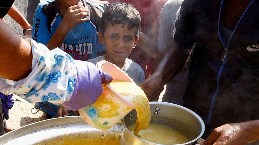 Palestinians gather to receive food cooked by a charity kitchen, in Khan Younis