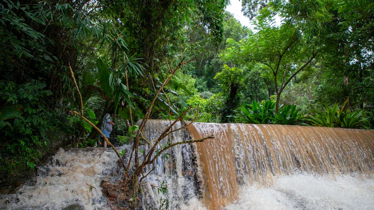 A visitor stands near flash floodwaters on Doi Suthep after continuous rainfall. The flooding in Chiang Mai were caused by continuous rainfall, electronics shop, resulting in runoff from Doi Suthep flowing into low-lying areas. The heavy rain also caused the Ping River to overflow at several points in the city, damaging homes and causing traffic congestion on many roads.