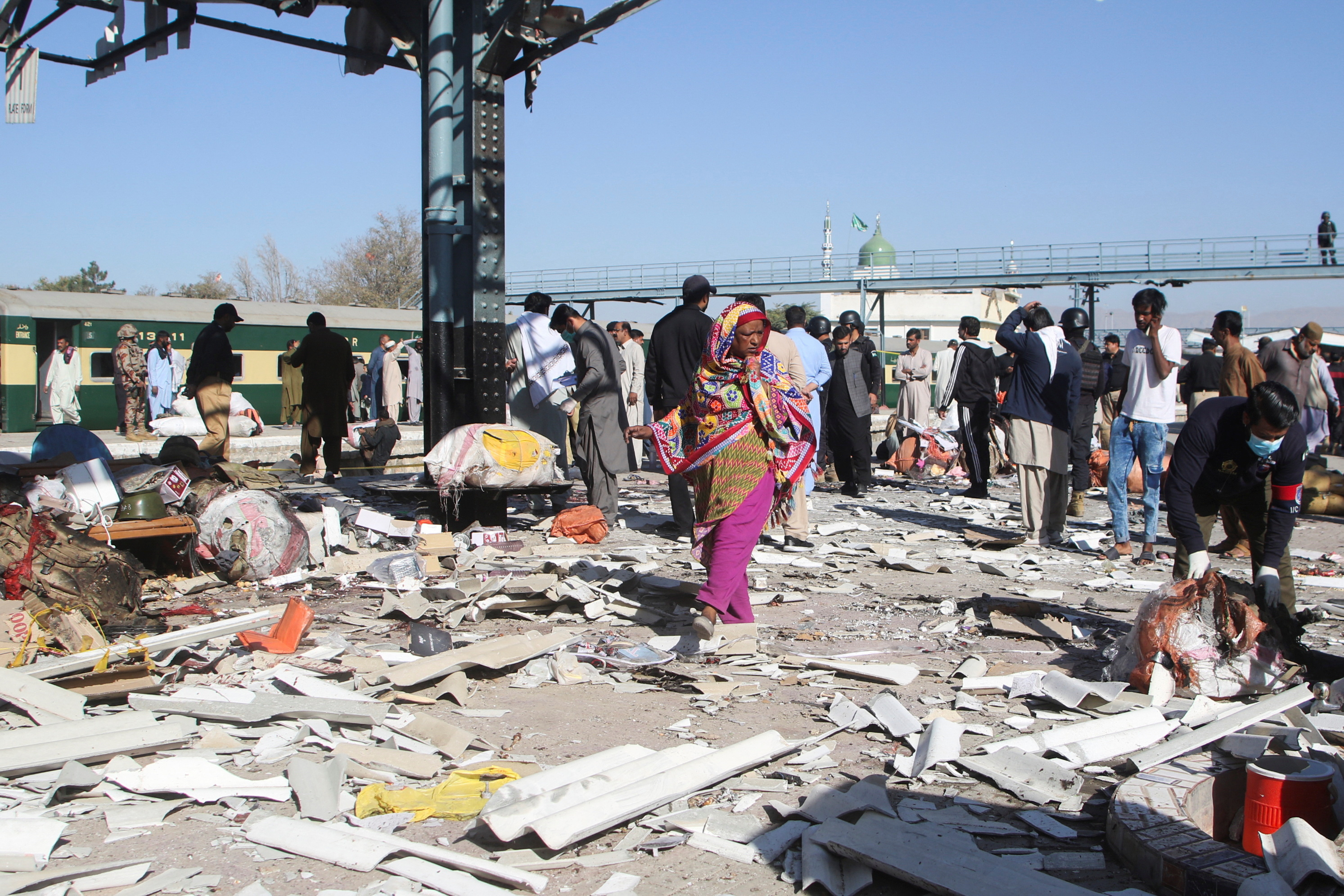 Woman walks amid the debris after a bomb blast at a railway station in Quetta