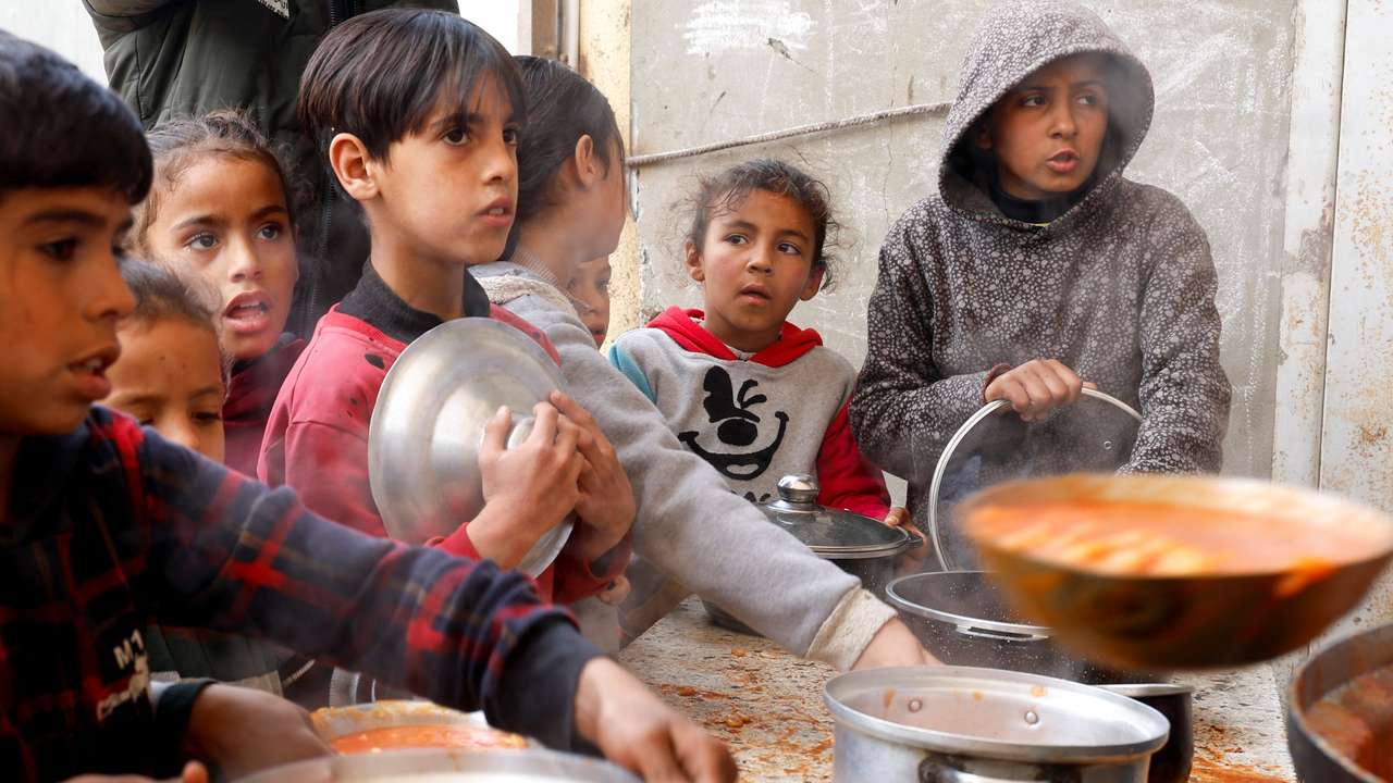 FILE PHOTO: Palestinians gather to receive food cooked by a charity kitchen, in Khan Younis