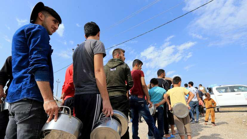 FILE PHOTO: Syrian displaced families, who fled violence after the Turkish offensive in Syria, stand in queue to get their food from Barzani charity at a refugee camp in Bardarash on the outskirts of Dohuk