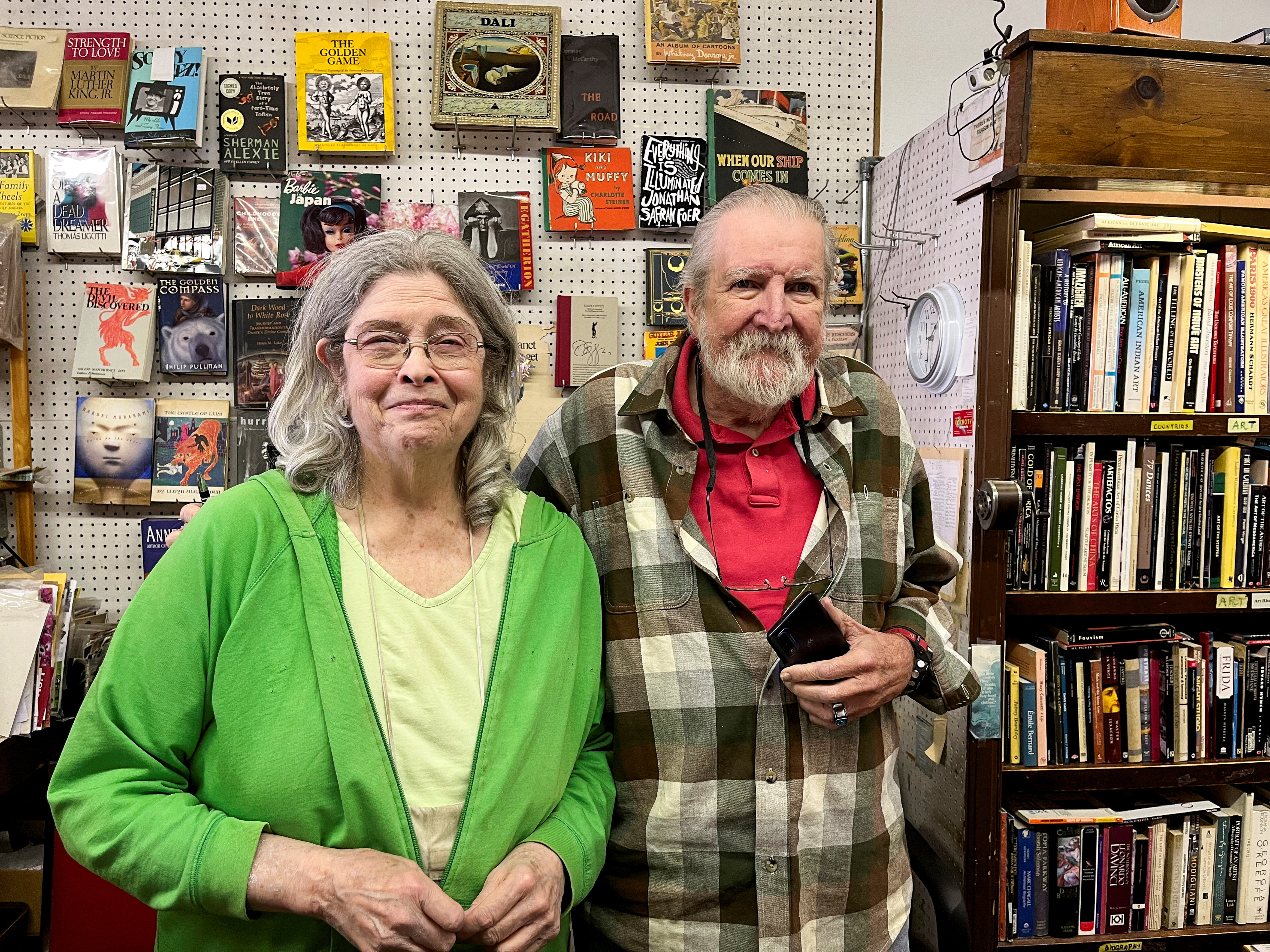 Martha Sempliner and John Veverka, both supporters of Vice President Kamala Harris, pose for a picture behind the counter at the Library Bookstore in Ferndale