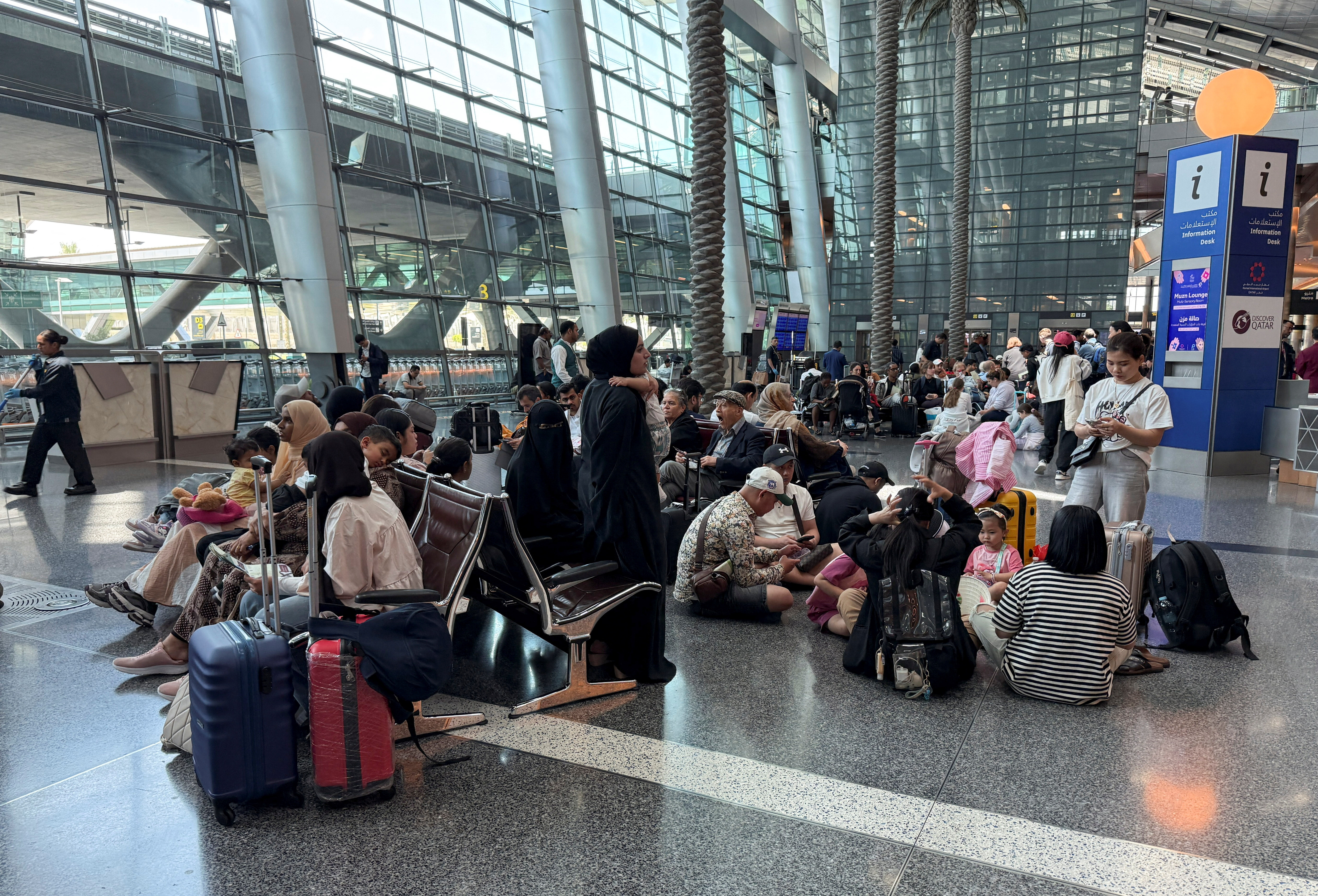 People sit at Hamad International Airport, in Doha