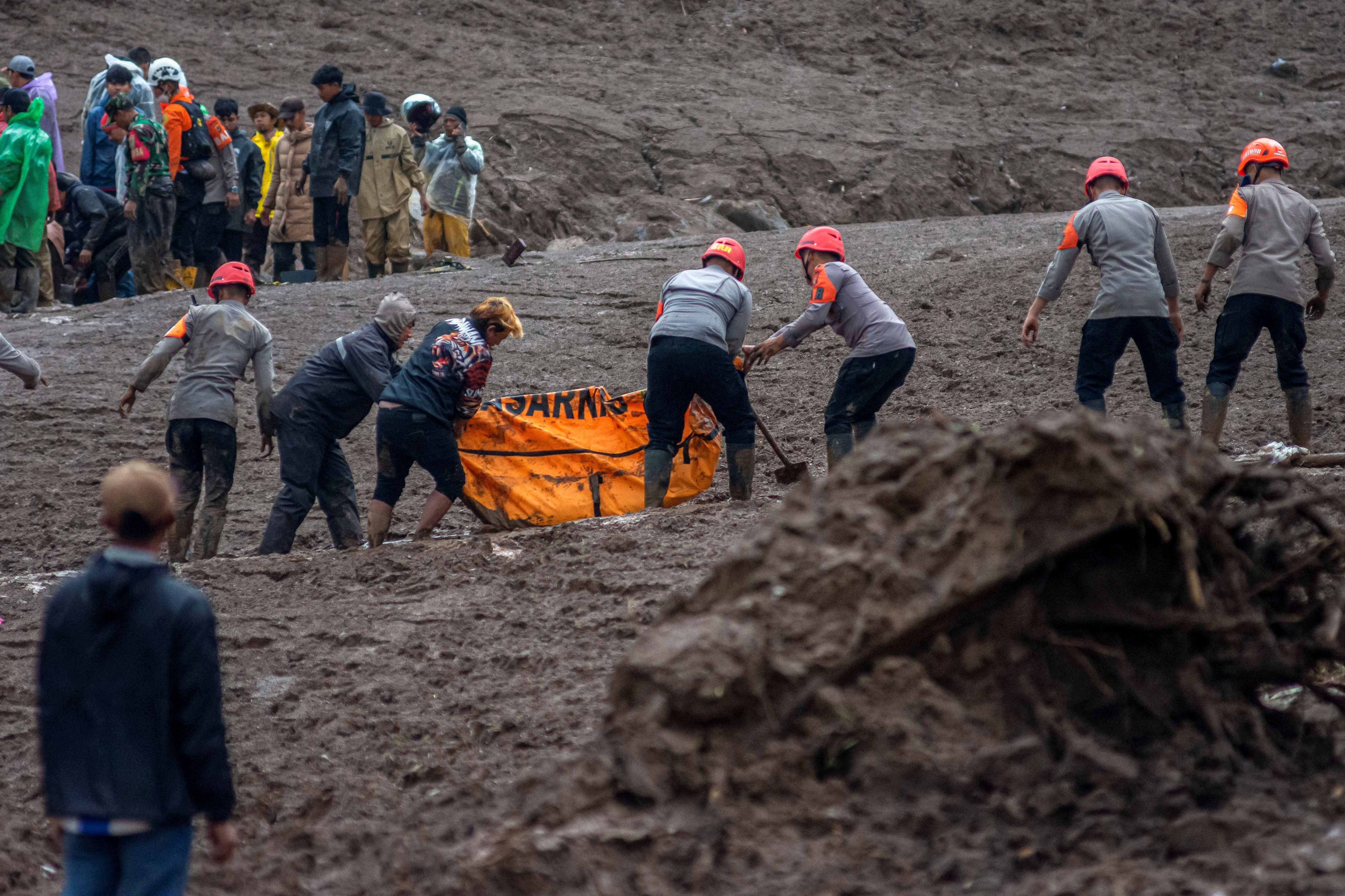 Indonesian rescue members carry a body bag containing the remains of a victim from the site of a landslide after it hit Pasirlangu village, West Bandung