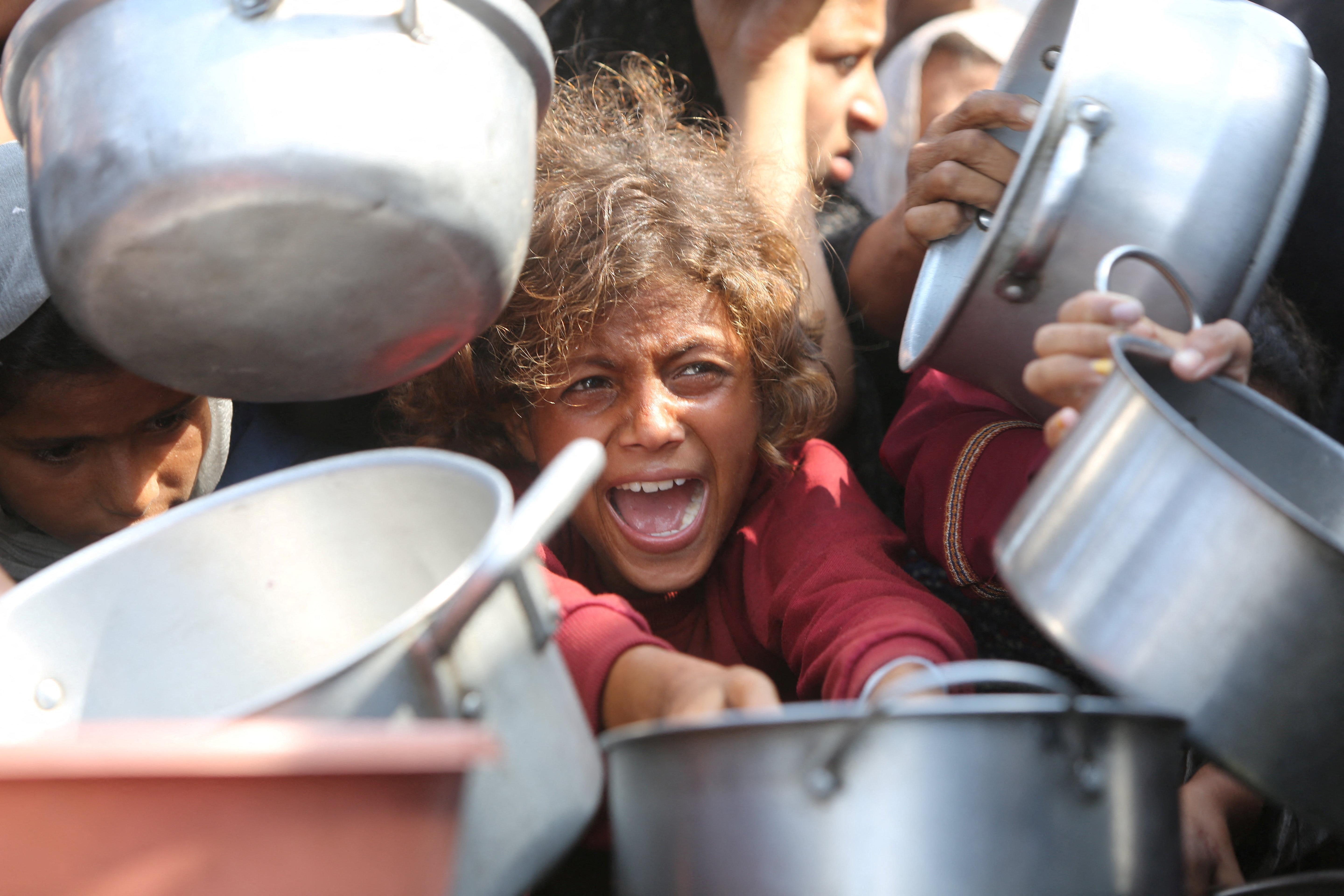 Palestinians wait to receive food from charity kitchen in Khan Younis