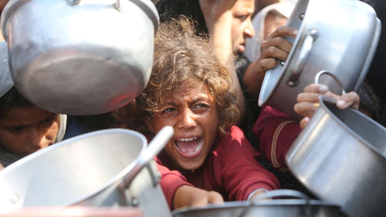 Palestinians wait to receive food from charity kitchen in Khan Younis