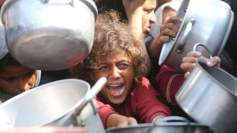 Palestinians wait to receive food from charity kitchen in Khan Younis