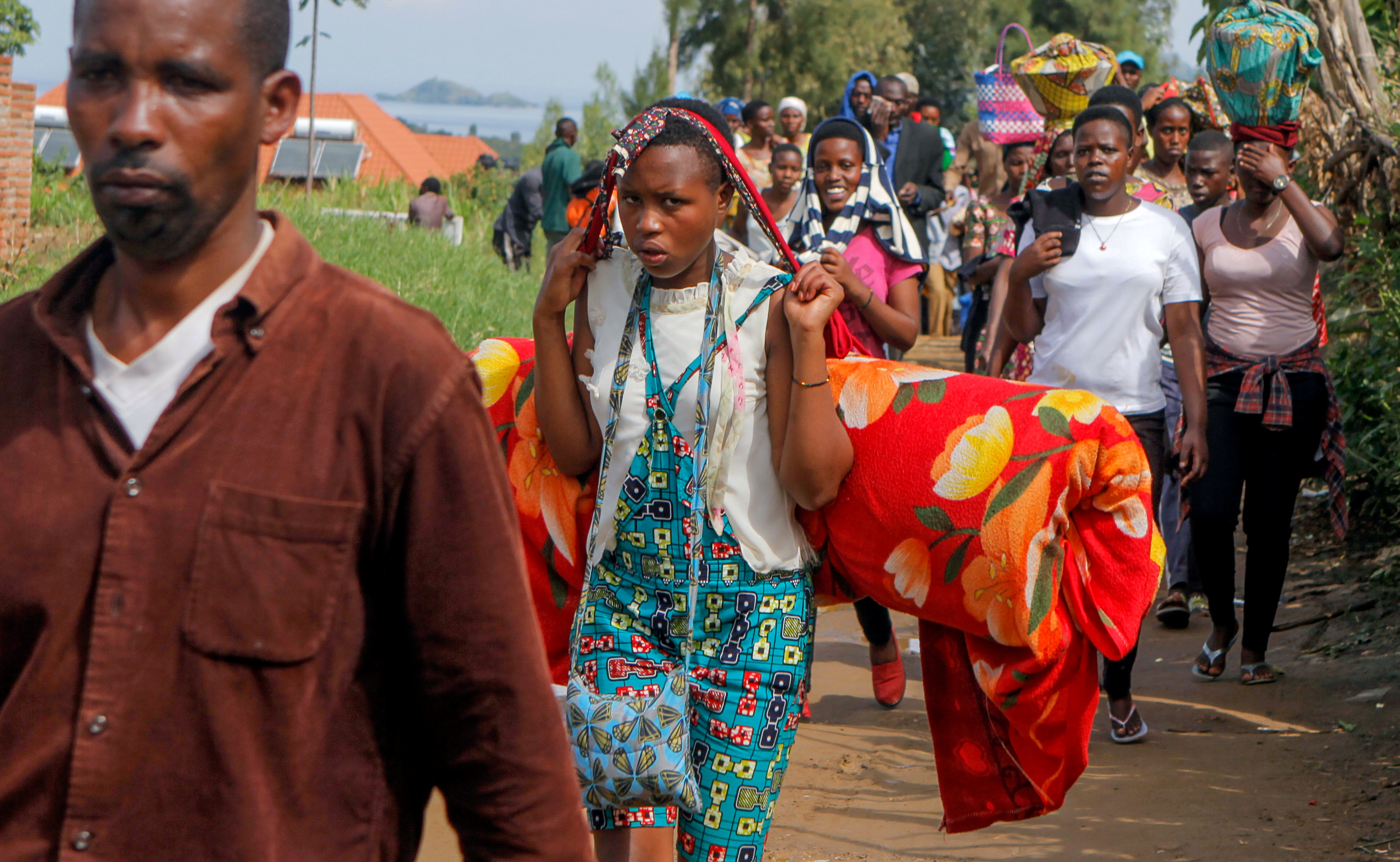 Refugees from the Democratic Republic of Congo carry their belongings as they walk near the UNHCR offices in Kiziba refugee camp in Karongi District