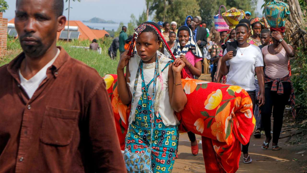 Refugees from the Democratic Republic of Congo carry their belongings as they walk near the UNHCR offices in Kiziba refugee camp in Karongi District
