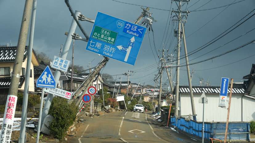 Road signs are tilted over a road damaged by the January 1 earthquake in Nishiaraya