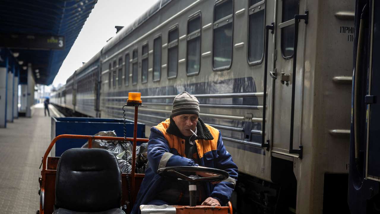 A worker of the Ukrzaliznytsia Ukrainian Railway company drives a luggage cart past a stationary train at the main train station in Kyiv