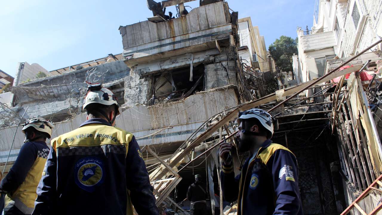 Civil defence members stand at a damaged site, after Israel carried out an air strike on the Syrian capital Damascus on Thursday, as reported by Syria's state news agency, in Damascus