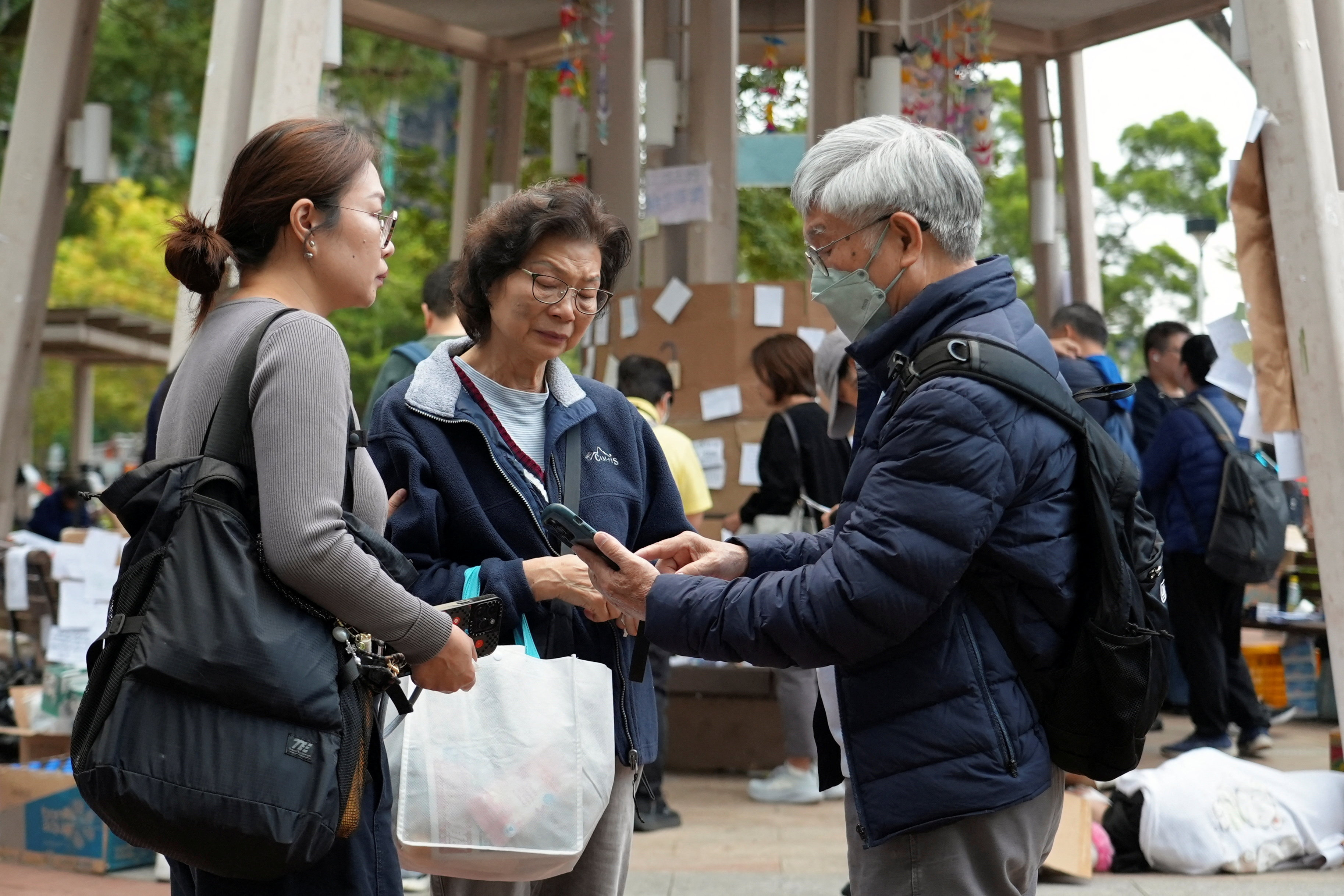 Residents of Wang Fuk Court housing complex gather with their daughter at a nearby park following the deadly fire in Hong Kong