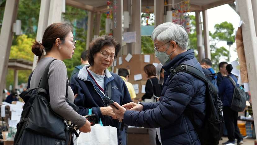 Residents of Wang Fuk Court housing complex gather with their daughter at a nearby park following the deadly fire in Hong Kong