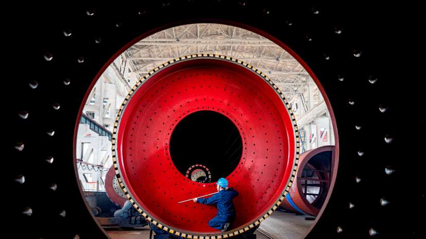 An employee measures a newly manufactured ball mill machine at a factory in Nantong, Jiangsu