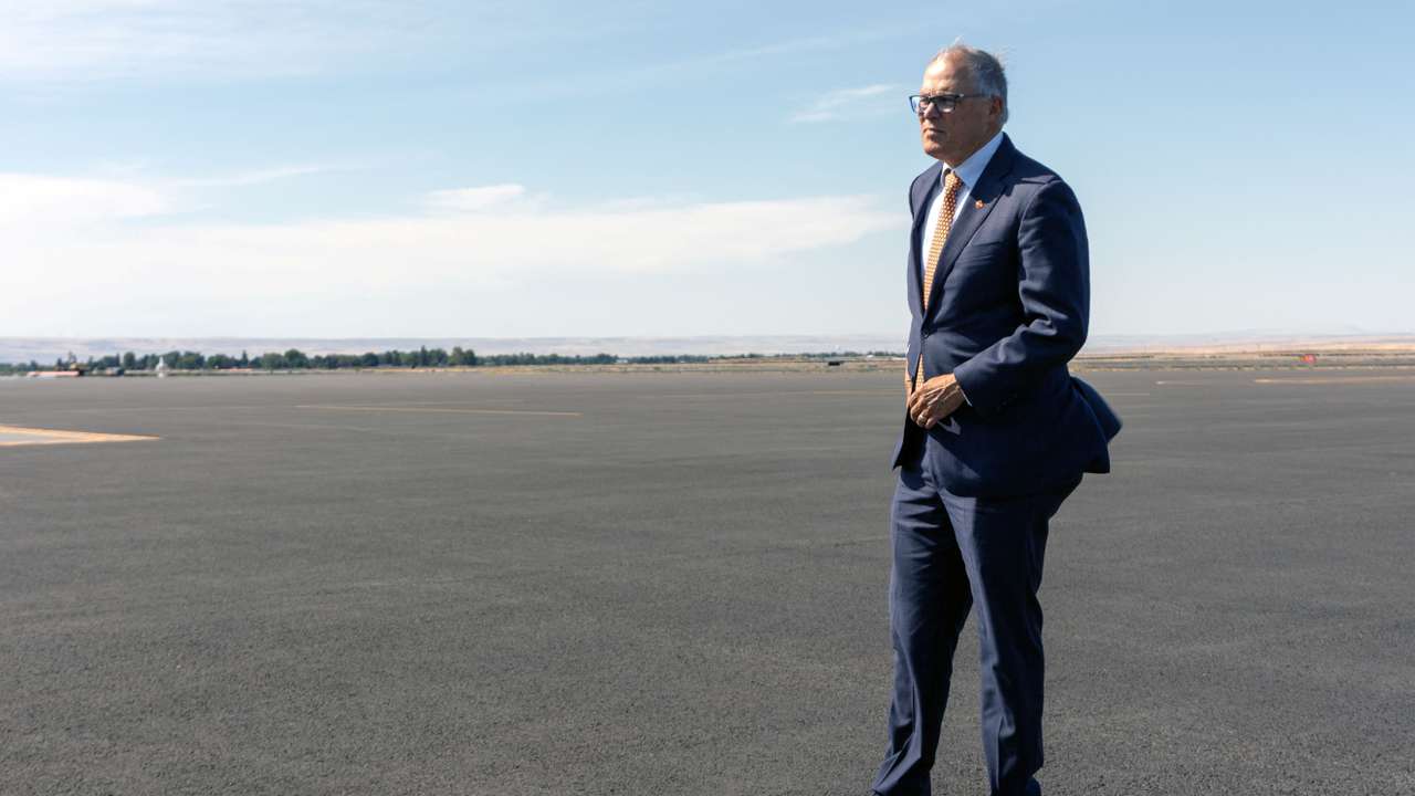 Washington Governor Jay Inslee stands on the tarmac while traveling to an event in Walla Walla, Washington