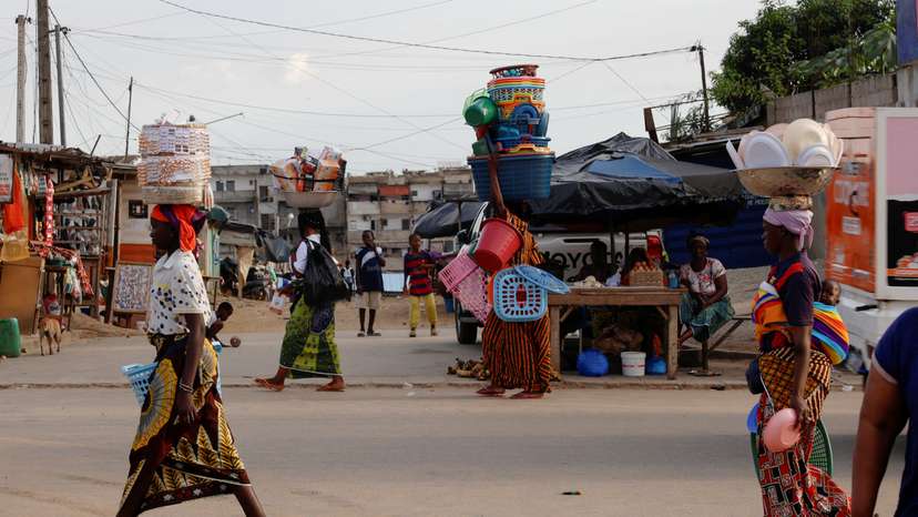 Vendors walk with their goods on the a street in Colombie, a slum of Abidjan