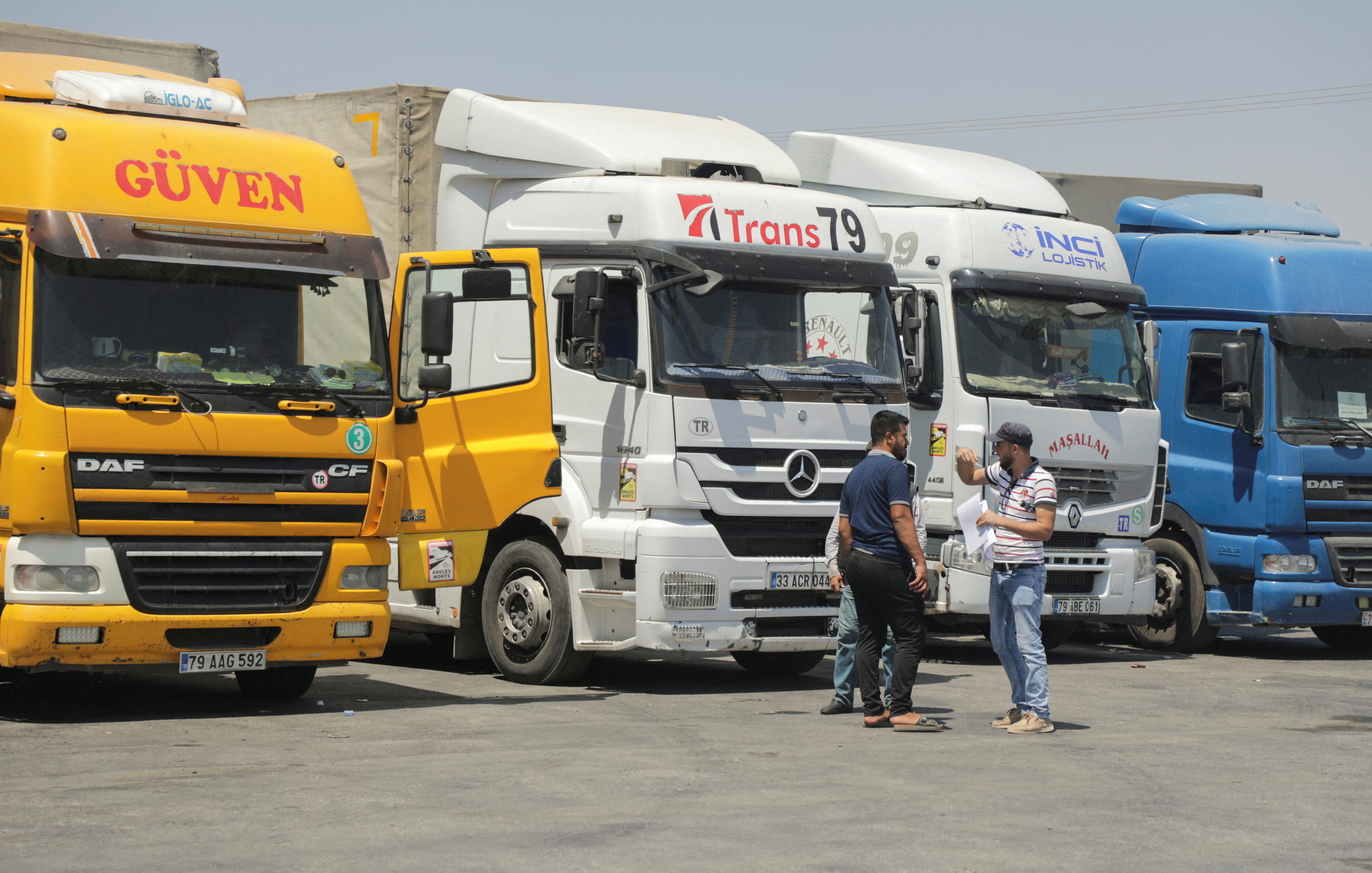 FILE PHOTO: People stand near trucks parked at Bab al-Salameh border crossing in Aleppo countryside