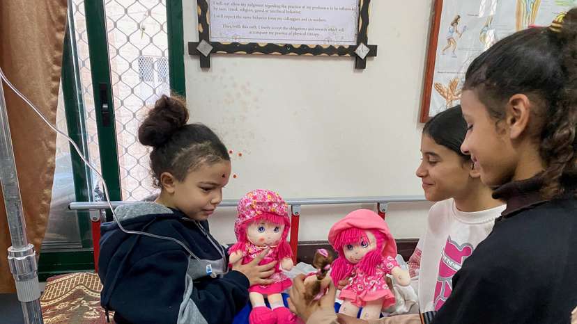 Displaced orphaned Palestinian girl plays with dolls at hospital in Deir Al-Balah