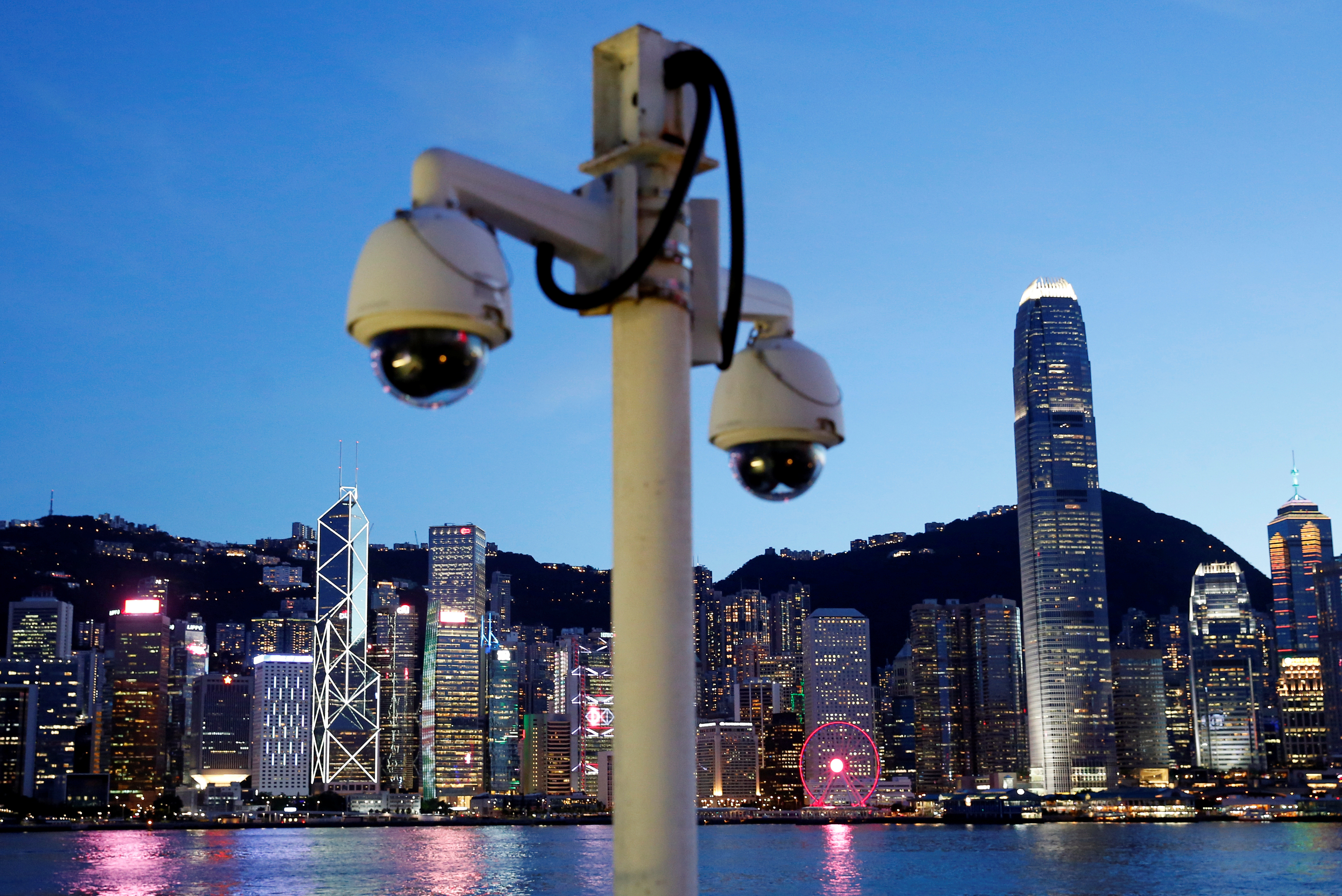 Pair of surveillance cameras are seen along the Tsim Sha Tsui waterfront as skyline buildings stand across Victoria Harbor in Hong Kong