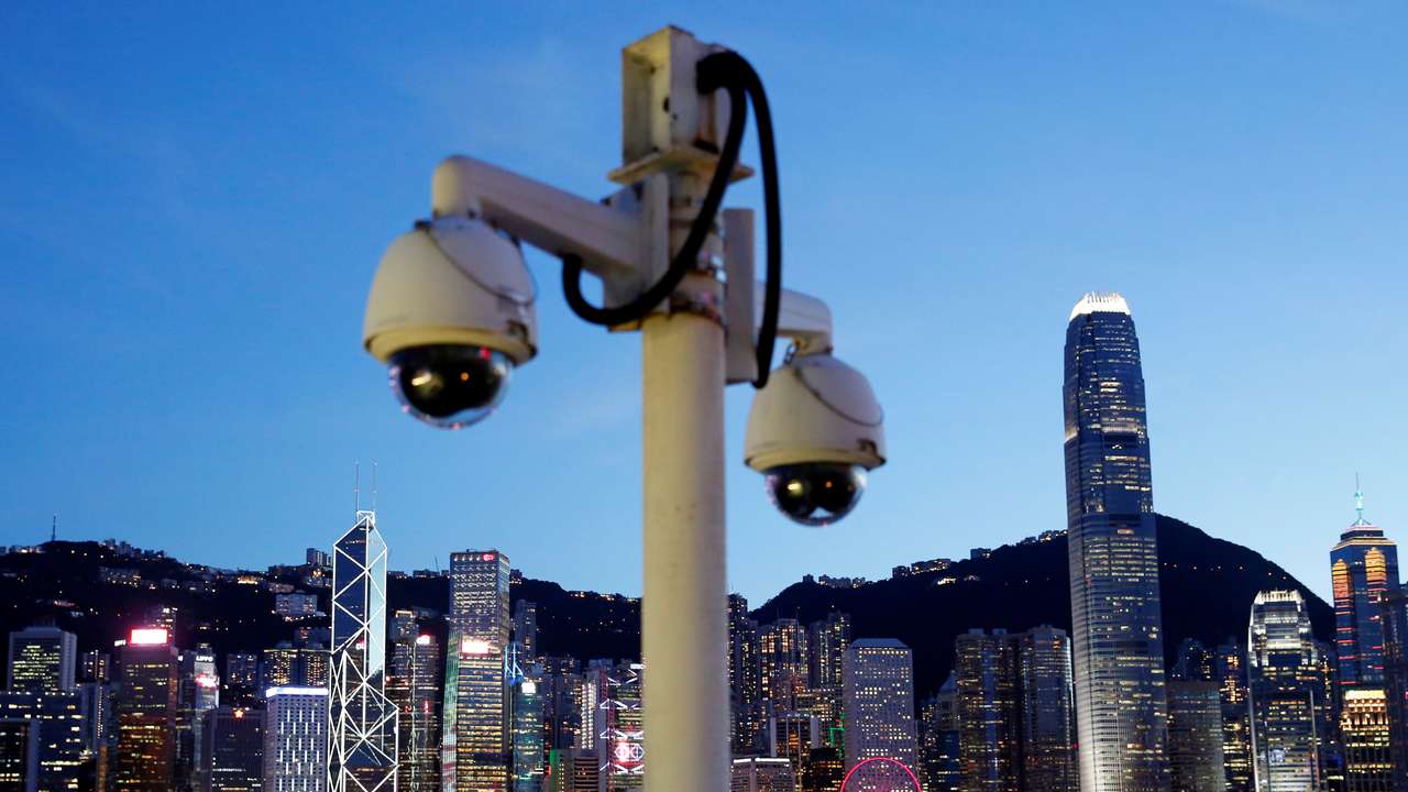 Pair of surveillance cameras are seen along the Tsim Sha Tsui waterfront as skyline buildings stand across Victoria Harbor in Hong Kong