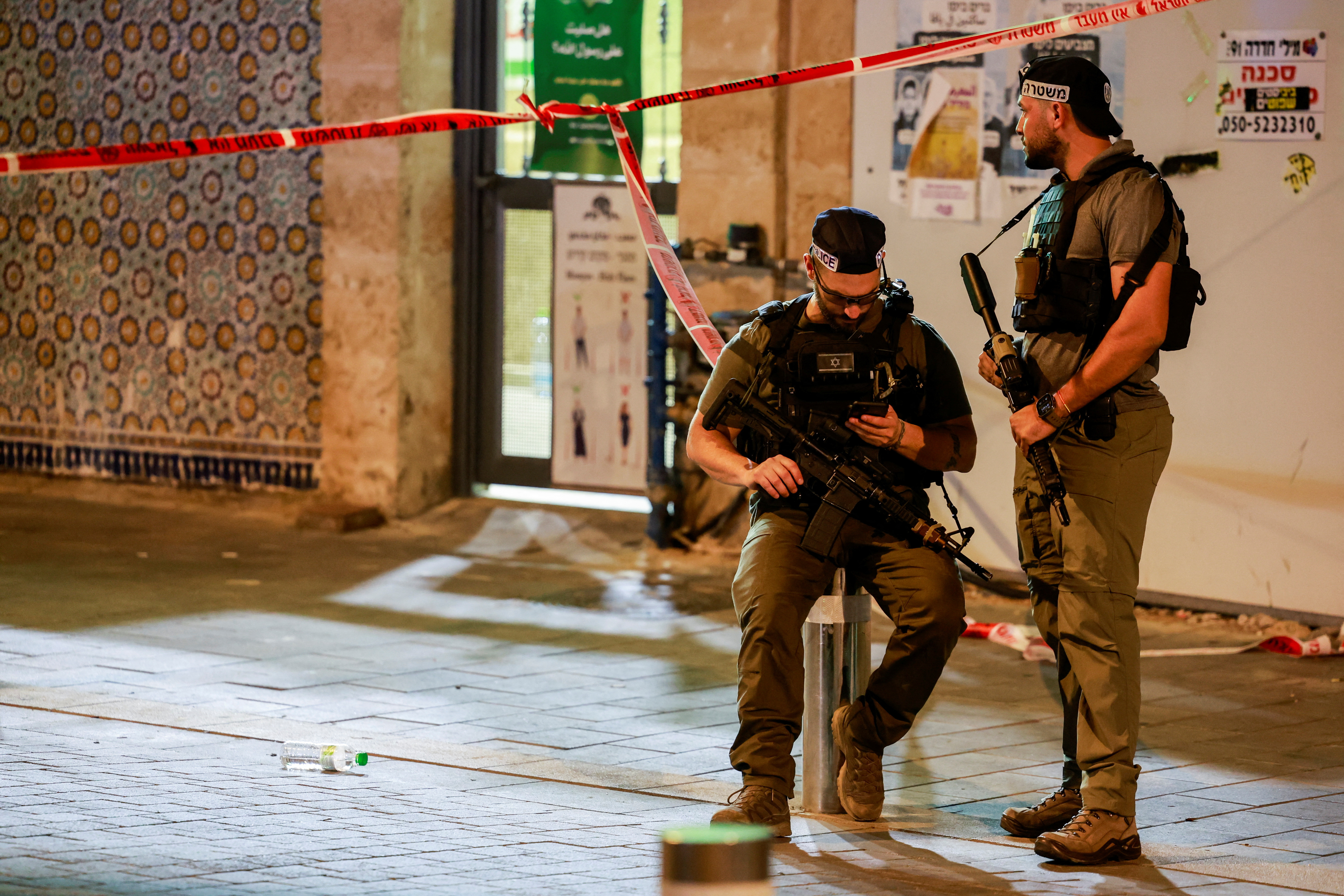 Police officers hold weapons, near the scene of a shooting attack in Jaffa