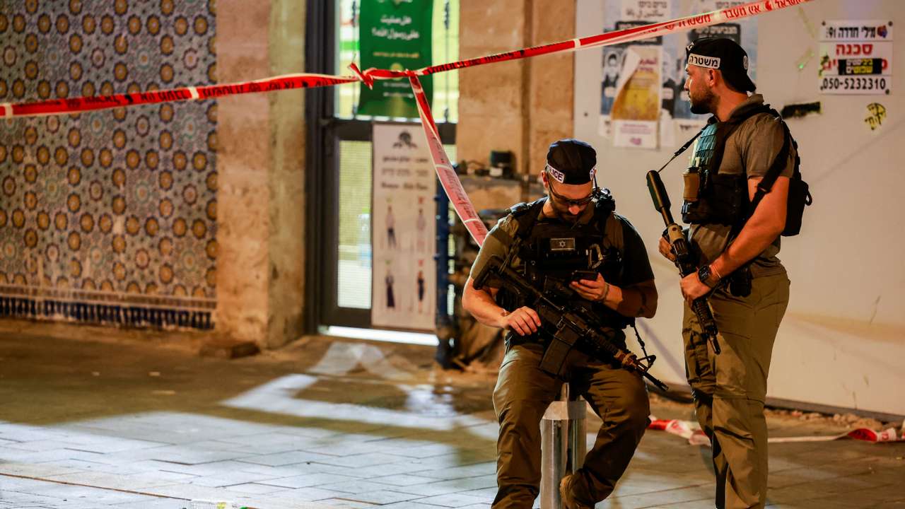 Police officers hold weapons, near the scene of a shooting attack in Jaffa