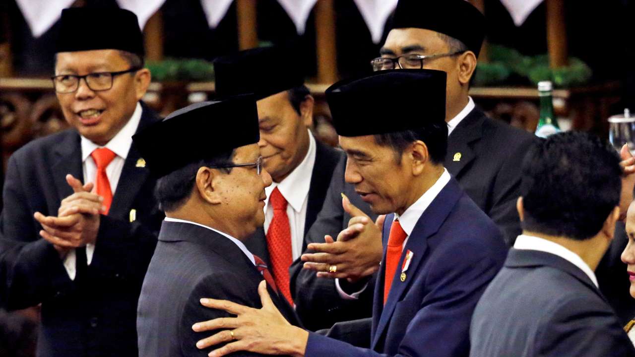 FILE PHOTO: Indonesian President Joko Widodo is congratulated by the Gerindra Party Chairman Prabowo Subianto, who was his former rival in April's election, after his presidential inauguration for the second term, at the House of Representatives building