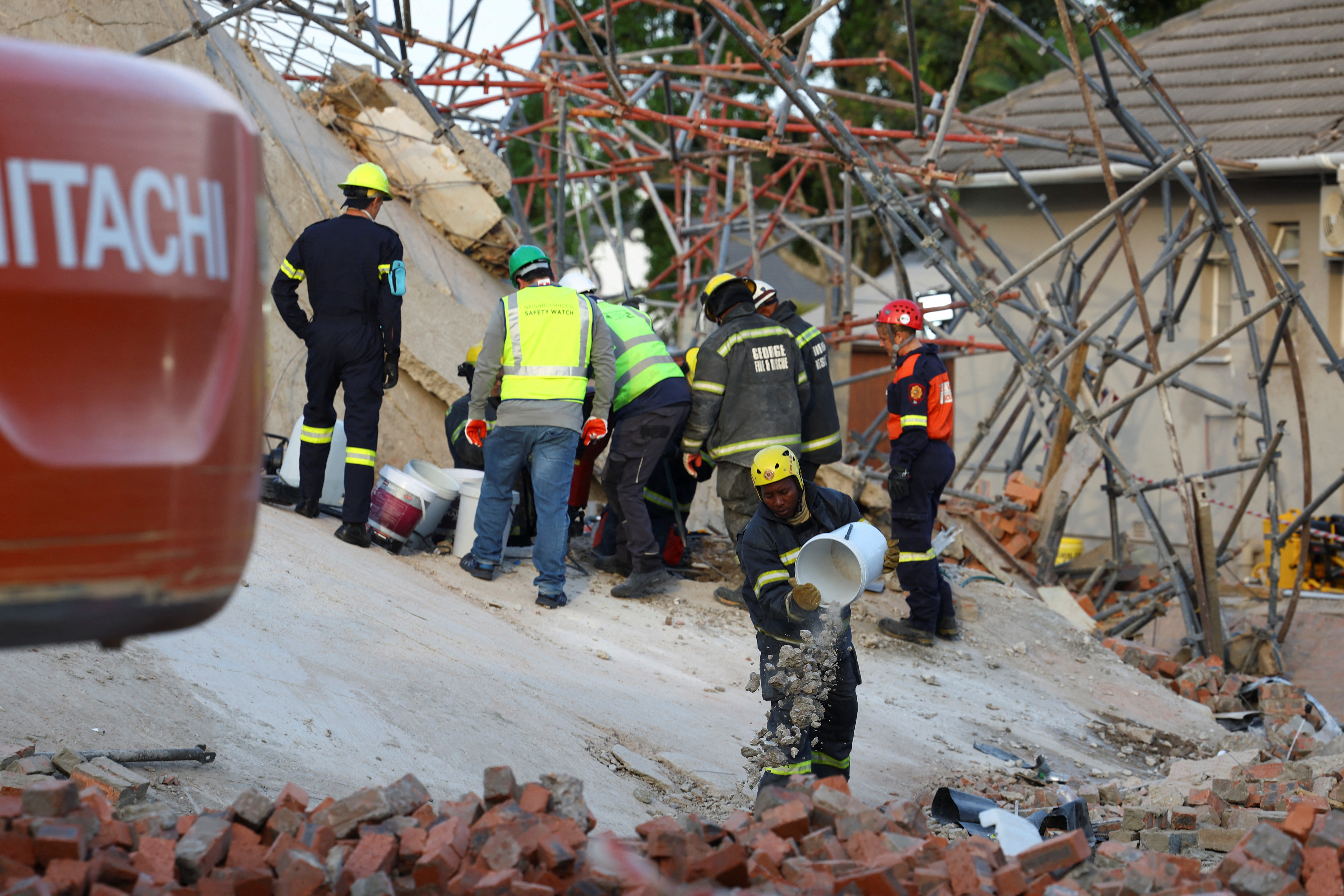 Rescuers work to rescue construction workers trapped under a building that collapsed in George